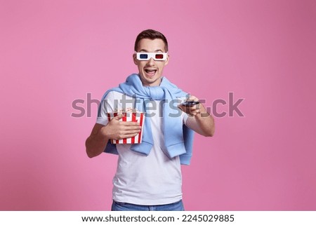 man using remote controller watching movie with big bucket of popcorns Royalty-Free Stock Photo #2245029885