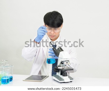 Asian male student scientist in reagent mixing laboratory In a science research laboratory with test tubes of various sizes and microscopes. on the table in  laboratory chemistry lab white background.