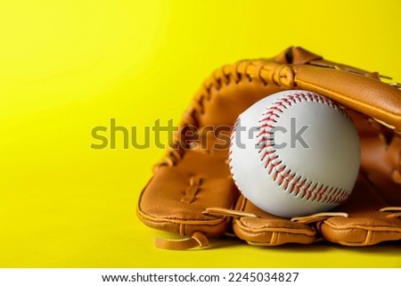 Catcher's mitt and baseball ball on yellow background, space for text. Sports game