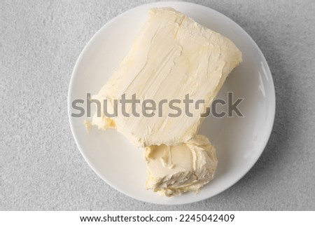 Plate with tasty homemade butter on white textured table, top view