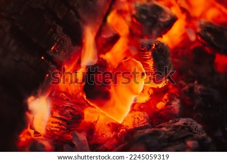Dark red coals and burnt piece of paper in the form of heart, close up. Concept of broken heart, end of relationships and devastation Royalty-Free Stock Photo #2245059319
