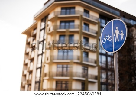 Road sign in front pedestrian and bicycle zone against building.