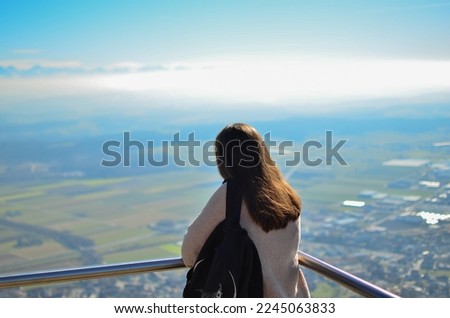 Woman with a backpack. A girl with a black backpack looks at a beautiful view. Photo in the mountains. Photo on the rock. 