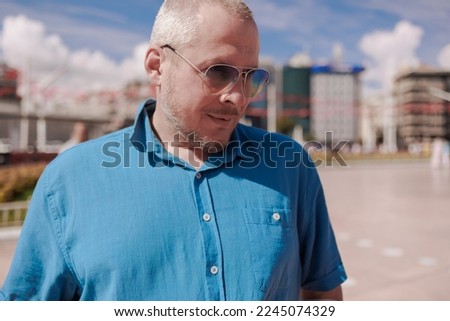 Adult man walking and posing in the city street on a sunny summer day