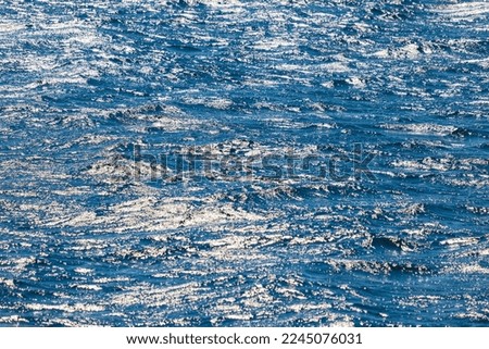 The texture of the water in the ocean with reflections in the sun, background for design.