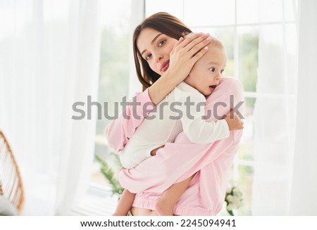 Young single mother lulling cradling her crying little small son daughter toddler infant newborn baby. Colics, teething health problems. Postnatal depression. Motherhood and childcare. Royalty-Free Stock Photo #2245094941
