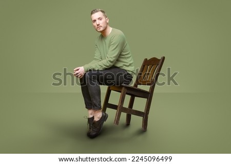 handsome guy tilt with chair while look at camera and pose  Royalty-Free Stock Photo #2245096499