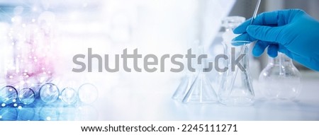 scientist in blur gloves with glass flask and test tube in research science lab banner background Royalty-Free Stock Photo #2245111271