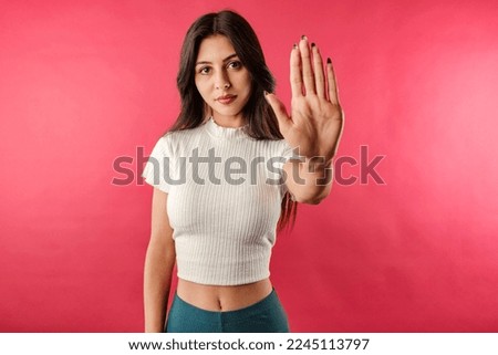 Young dark-haired woman wearing ribbed crop isolated over red background doing stop sing with palm of the hand. Warning expression with negative and serious gesture on the face.