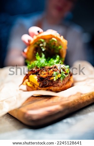 Chefs woman hand open burger with beaf and vegetables