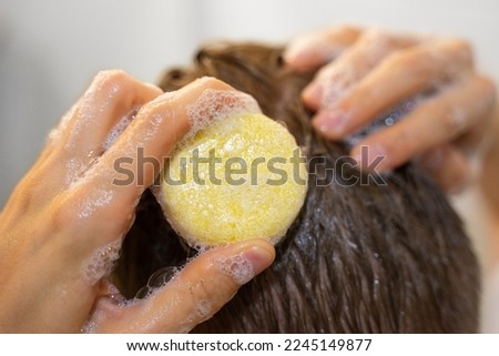 A man applies a solid shampoo bar to the hair. Man in the bathroom. Sustainable hair care, eco-friendly cosmetics. Plastic free, zero waste living, low water ingredients. Responsibility for nature. Royalty-Free Stock Photo #2245149877