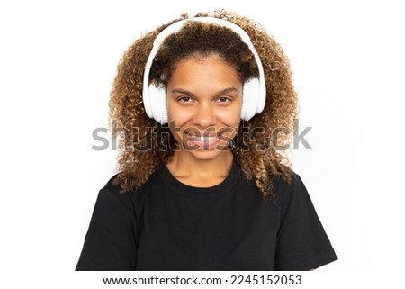 Happy African American woman wearing headphones. Pleased young female model with curly fair hair in black T-shirt looking at camera, smiling, listening to music or podcast. Modern technology concept