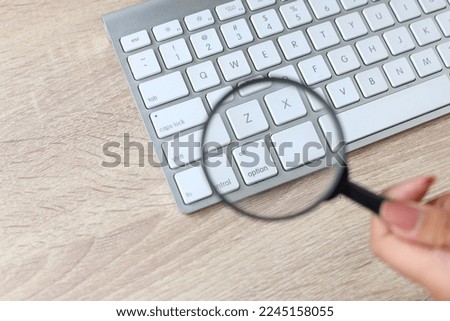 Magnifying glass look up letter on keyboard. Search Engine Optimization on office background.