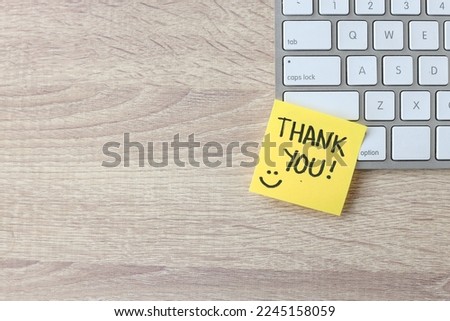 Top view of words thank you written on sticky note on keyboard over wooden background.  Royalty-Free Stock Photo #2245158059
