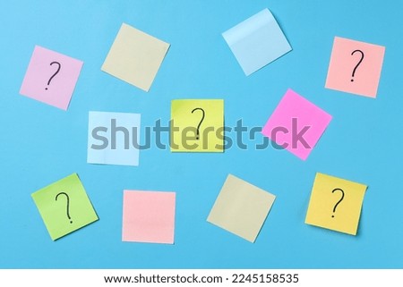 Question marks on sticky notes and colorful blank sticky notes for text space on blue background. 