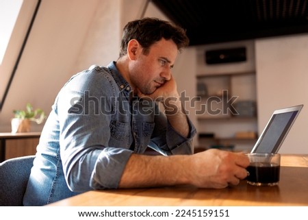 Smiling bearded caucasian businessman working on laptop at home office. Brunette student use computer distance learning surrounding video call learning, watching online webinar or seminar