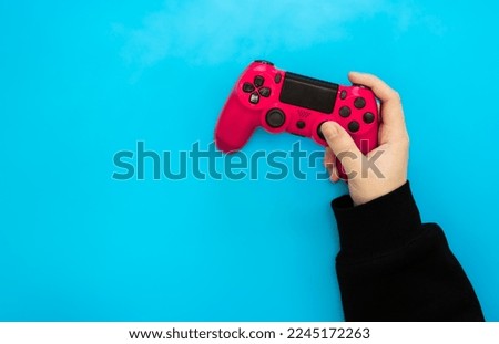 Pink gamepad in male hands on a blue background, flat lay, copy space.