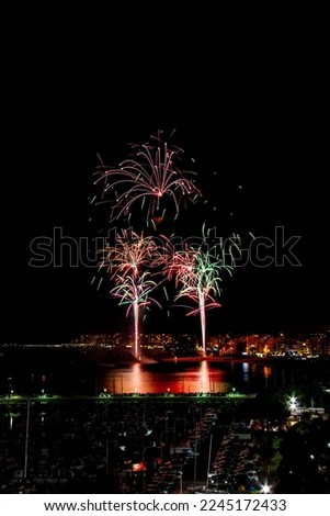 red, blue, yellow fireworks, black background, in the town of blanes
