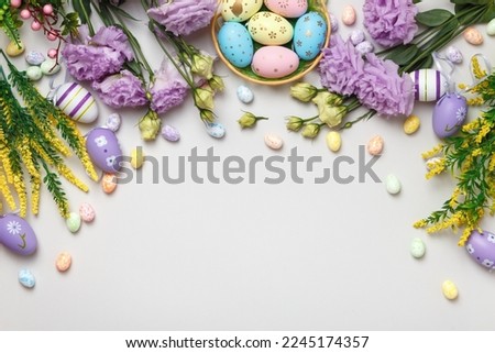 Easter composition. Top view eggs in basket purple yellow flowers on gray background