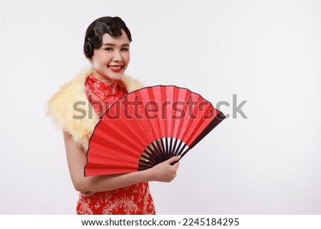 Smiling young beautiful asian woman in traditional chinese dress holding red folding chinese fan on isolated white background.