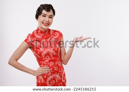 Smiling young beautiful asian woman in traditional chinese dress presenting on isolated white background.
