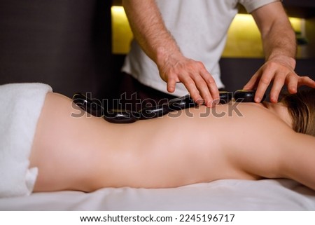Massage therapist putting warm stones on a womans back