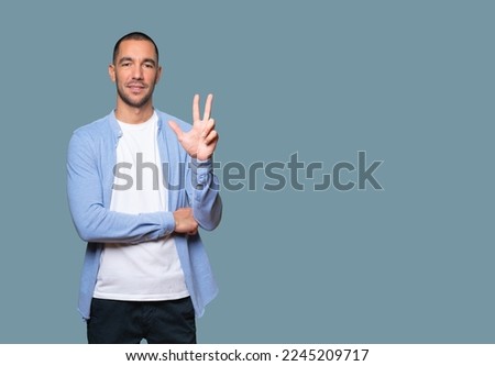 Young man making a number three gesture