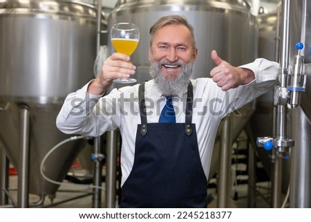 Pleased brewery technologist approving a new beverage before the camera