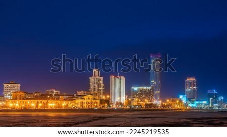Yekaterinburg city with Buildings of Regional Government and Parliament, Dramatic Theatre, Iset Tower, Yeltsin Center, panoramic view at Early Spring night. Ice in the river began to melt