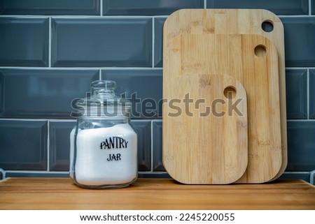 bamboo chopping preparation boards lined up on the worktop with a glass air tight jar with salt Royalty-Free Stock Photo #2245220055