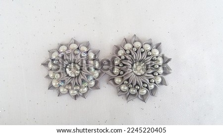 Handcrafted flower brooch made of gray ribbon and beads on a white background