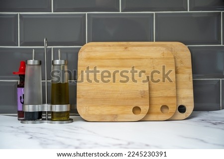glass bottles with pouring spouts for olive oil balsamic vinegar with bamboo boards on granite worktop with chilli bottle Royalty-Free Stock Photo #2245230391