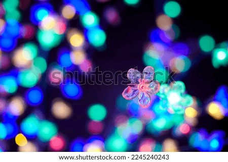 Colorful lights bokeh from decorative luminous flowers garlands at holiday, blurred festive background, abstract outdoor lights with boke. Multicolored flowers lights with beautiful bokeh at night