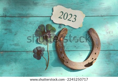 Horseshoe with lucky clover - 2023 greeting card horseshoe on wooden background - happy new year greetings, wishes	