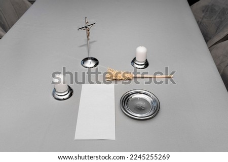 A steel caroling set lying on a gray tablecloth, traditional priest caroling in Poland, with an envelope with money.