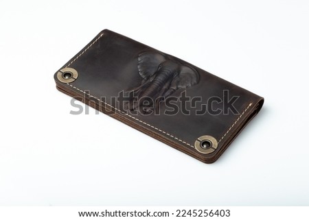 Big brown leather wallet on a button on a white background, elephant print.