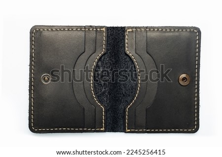 Black leather wallet on a button on a white background, wolf print. Top view
