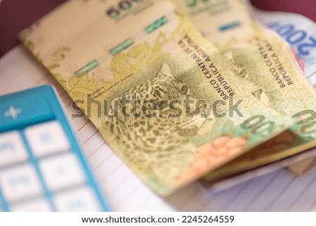 Argentine peso banknotes in close-up photo. A calculator and notebook in the composition. Argentine economy and finance.
