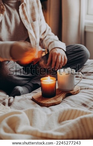 A caucasian man relaxing at home, lighting candle, drinking coffee in bed Royalty-Free Stock Photo #2245277243