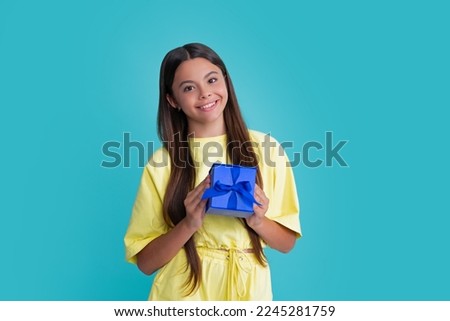 Happy girl face, positive and smiling emotions. Child with gift present box on isolated studio background. Gifting for kids birthday.