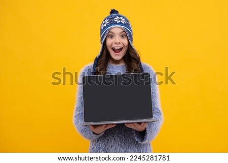 Winter school. Teenager school girl hold laptop in autumn clothes on yellow isolated studio background. Excited teenager girl.
