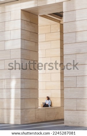 woman is resting after work, modern architecture, beige columns in business center or office building. urban. full-length photo.