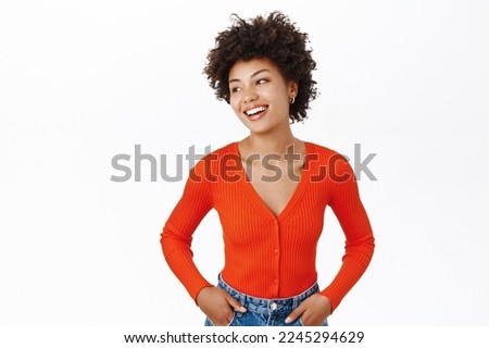 Portrait of smiling, beautiful african american woman with afro curly hair, wearing red blouse, standing over white background Royalty-Free Stock Photo #2245294629