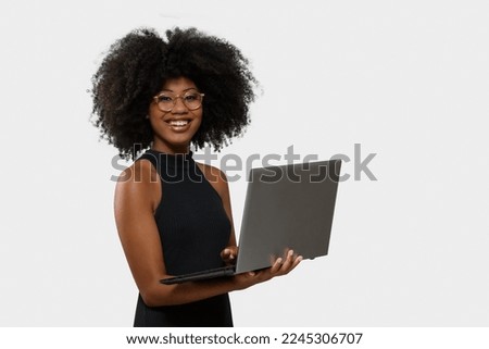 woman holding laptop computer typing on keyboard looking at camera, black woman Royalty-Free Stock Photo #2245306707