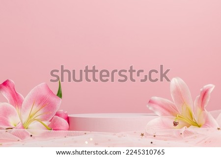 Blank cylinder podium with lily flowers on pink background with white glitter fabric. Display for product presentation