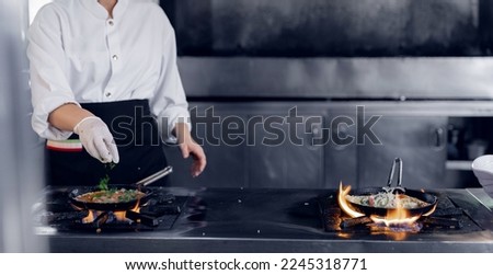 Professional chef and fire. Woman cooking food vegetables open fire, photo slow motion freeze time. Concept hotel service pan asian wok.