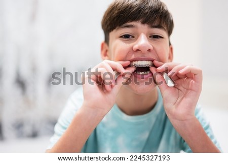 Teenager boy wear simulator orthodontic silicone invisible leveling braces for teeth.  Dental concept, orthodontics.  Royalty-Free Stock Photo #2245327193