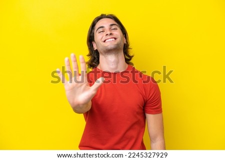 Caucasian handsome man isolated on yellow background counting five with fingers