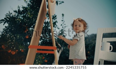 Baby girl paints outdoor in beautiful orange garden