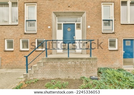 an apartment building with blue doors and steps leading up to the front door there is a brick wall in the background